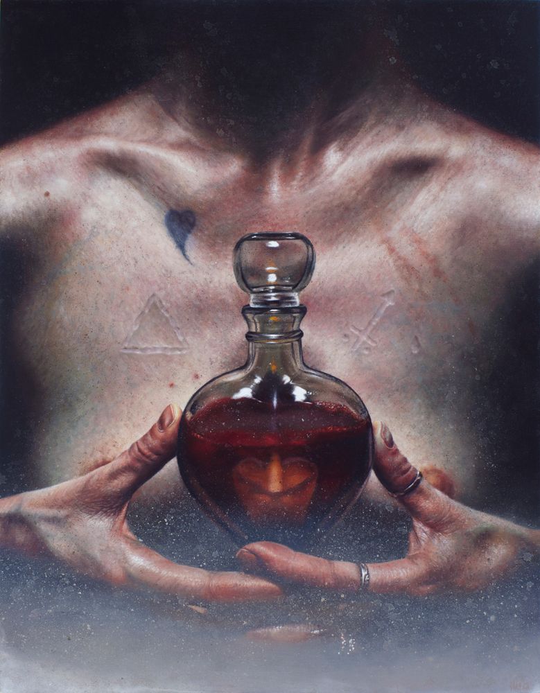 A close view of a bare chest and ringed hands framing a round glass bottle filled with dark red liquid, with a candle reflection visible inside.