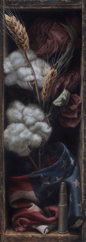 Vertical still life of cotton bolls, wheat stalks, wilted red roses, a draped American flag, and an upright brass bullet and cartridge against dark wooden shadowbox.